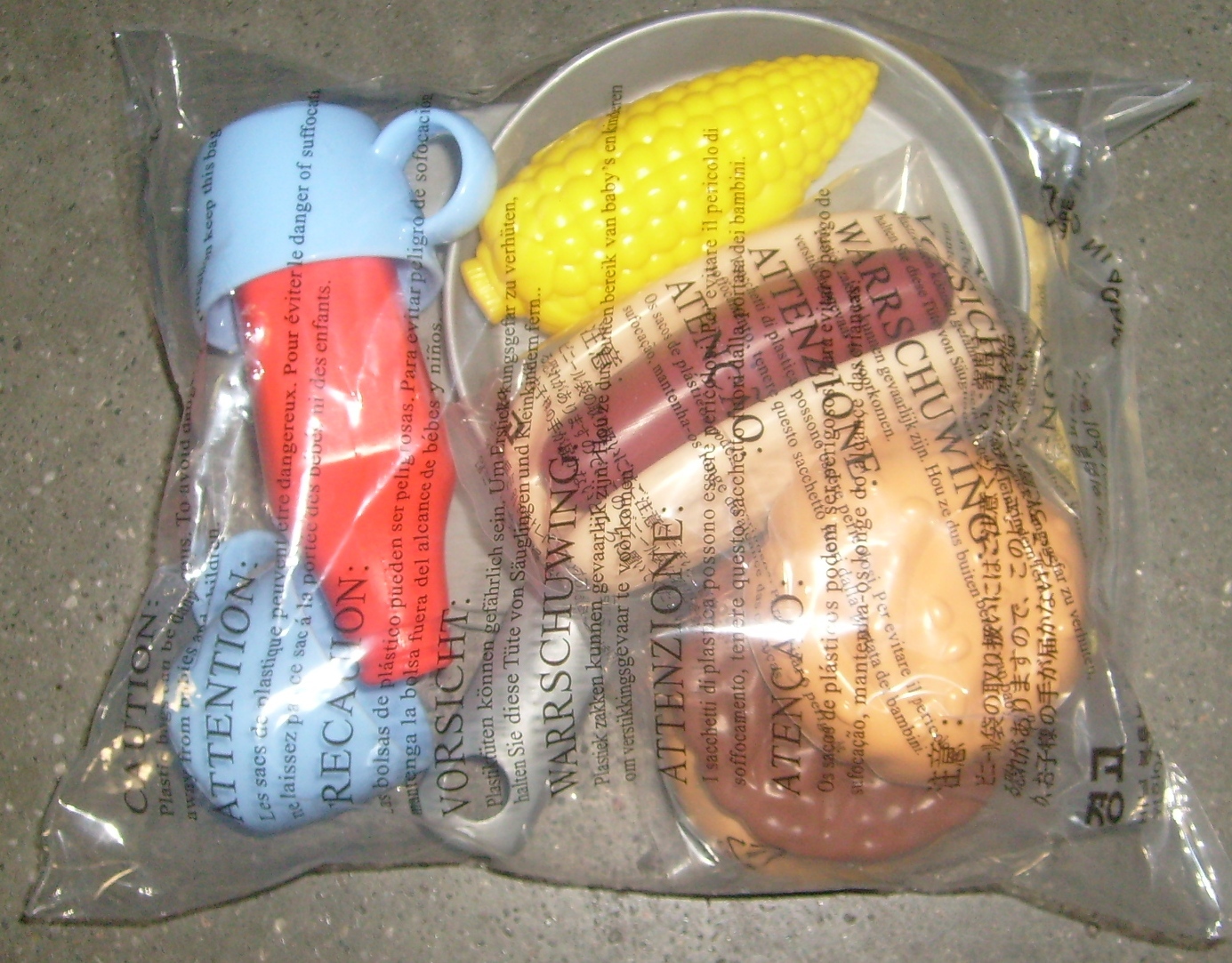 Food Accessory Pack includes Hotdog, Burger/bun, corn, ketchup, 2 cups, frying pan, 2 plates, 2 knifes, forks, spoons. Image